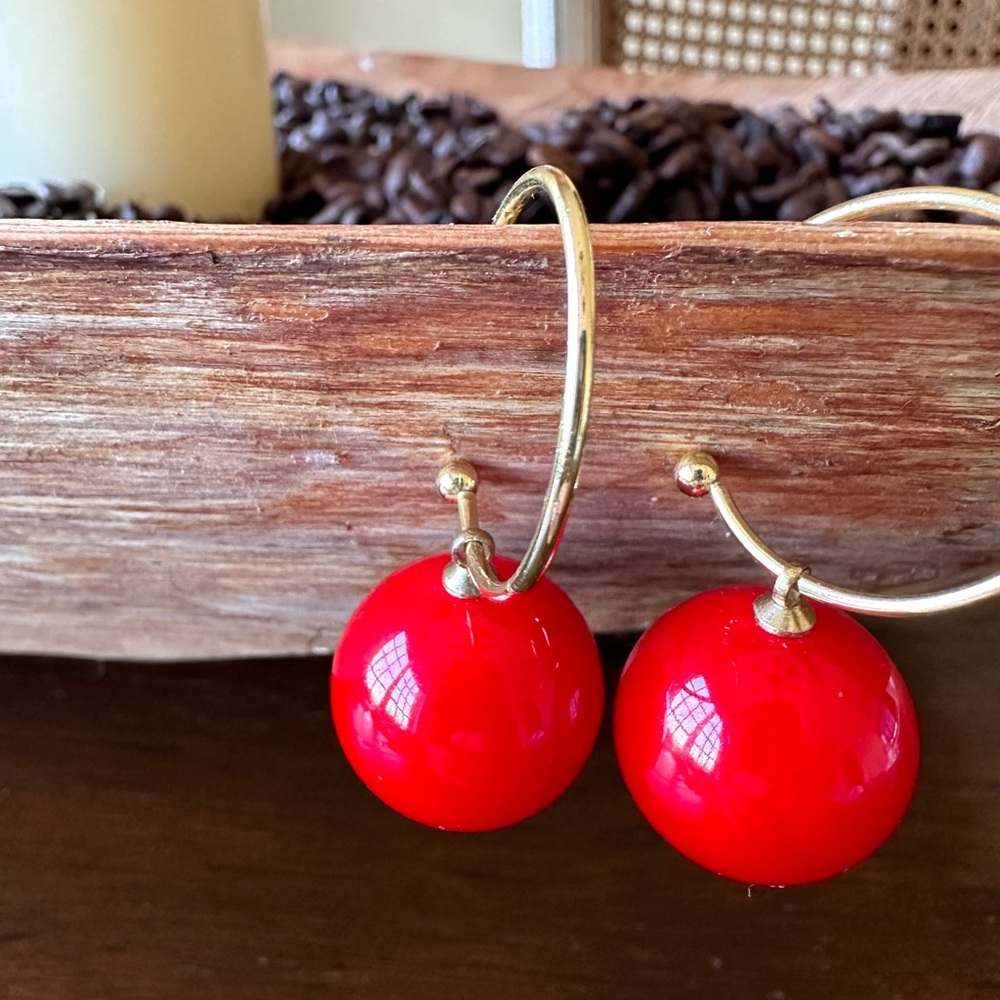 Gold tone hoop earrings with red acrylic balls